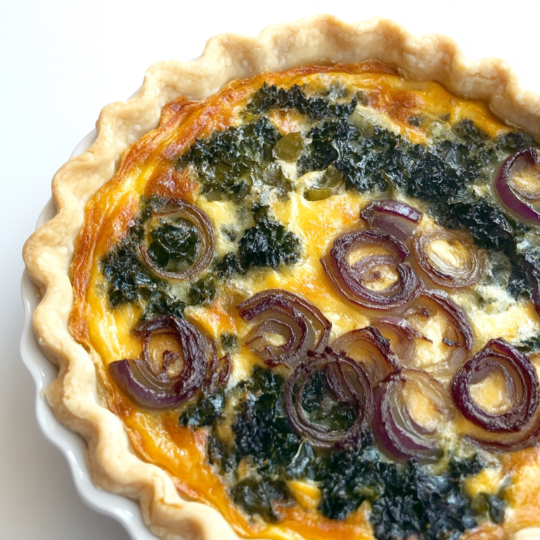 Freshly baked kale and onion quiche with golden crust, filled with sautéed kale, caramelized onions, and melted cheese.1
